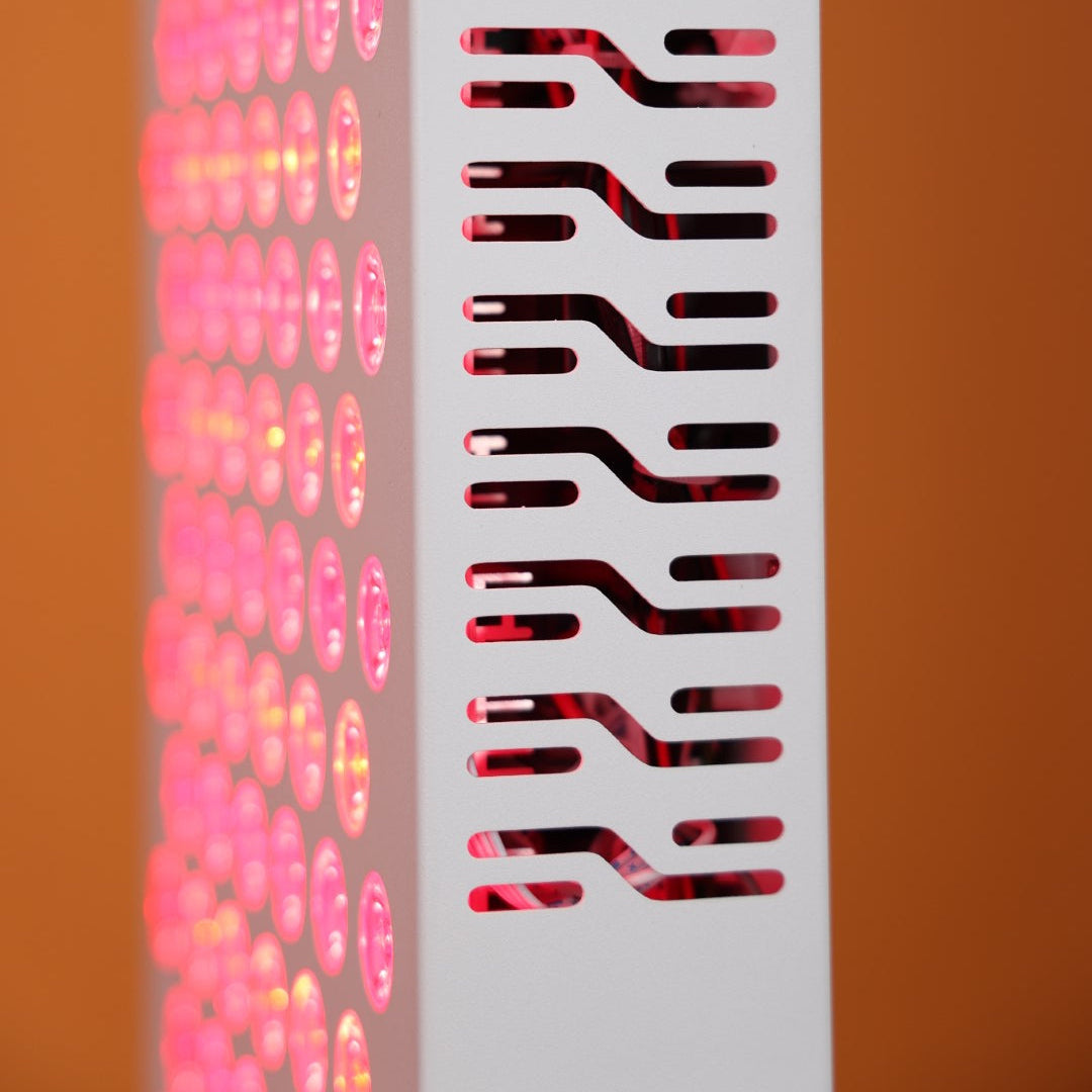 Close-up view of the side vent design of the Nicebeam Red Light Therapy Panel, showcasing its intricate pattern for efficient heat dissipation. The glowing red and near-infrared LEDs are visible through the vents, emphasizing the panel's functional and sleek design, set against a vibrant orange background.